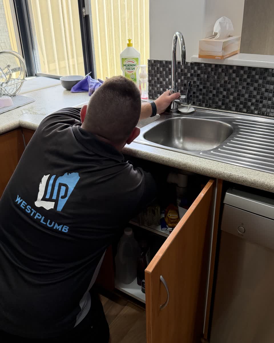 Brent working under a kitchen sink
